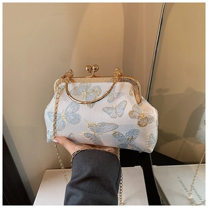 Detail of vintage hand-held bag with blue butterfly embroidery and gold metal frame