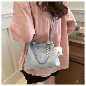 Detail of light blue bucket bag with woven handle and plush bunny charm on a pink shirt