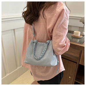 Detail of light blue bucket bag with woven rope handle and delicate leather texture