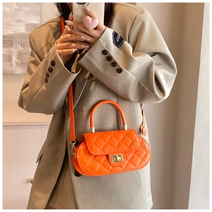 Detail showing orange quilted crossbody bag with golden lock and adjustable strap