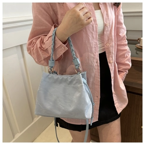 Close-up of light blue pleated bucket bag with textured leather and woven handle
