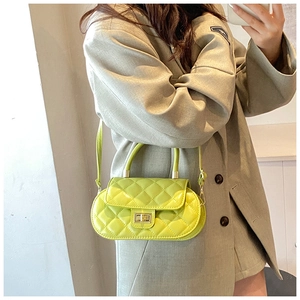 Close-up of a neon green quilted baguette bag with a gold lock worn by a model in gray suit