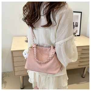 Pink bucket bag with woven handle and plush charm detail on soft polyester fabric