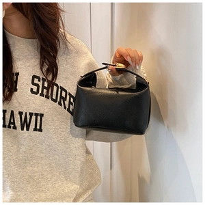 Detail shot of black faux leather handbag with embossed letters and gold metal clasp