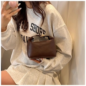 Detail of a brown leather pillow bag with embossed text and gold metal buckle closure