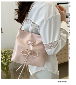 Detail of light pink bucket bag with drawstring bow on white lace outfit