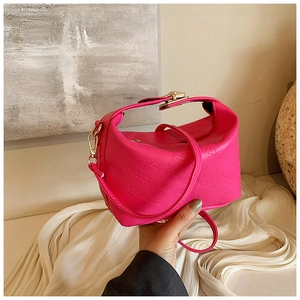 Detailed close-up of rose red embossed leather bag with golden metallic hardware buckle