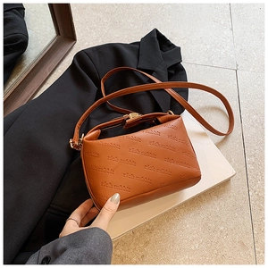 Close-up of caramel leather crossbody bag featuring rich rabbit embossed pattern and gold buckle