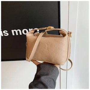 Detail of minimalist beige handbag featuring rich rabbit embossed pattern and gold buckle
