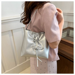 Detail of silver metallic tote bag with decorative cross-tie bow design on shoulder strap