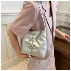 Detail of silver tote bag with drawstring bows and metallic finish on shoulder