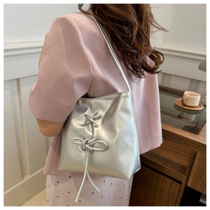 Detail of silver metallic underarm bag with knot rope decoration on model