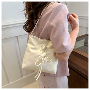 Detail of cream leather bucket bag with bow drawstring and metal eyelet accents