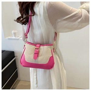 Detail of a beige canvas crossbody bag with pink leather straps and gold buckle