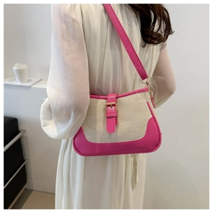 Detail of canvas and fuchsia leather shoulder bag with gold hardware worn by model