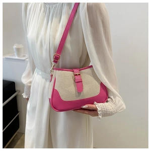 Detail of fuchsia leather and beige canvas stitching on a modern women's shoulder bag