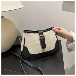 Detail of canvas shoulder bag with black leather trim and elegant gold metal buckle