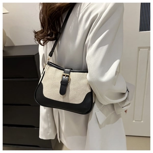 Detail of vintage canvas shoulder bag with black leather trim and metal buckle on model