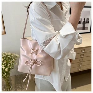 Detailed close-up of light pink tote bag with a decorative bow and leather texture