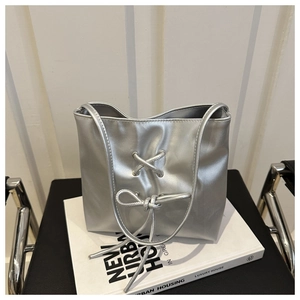 Detailed view of silver metallic bag featuring a textured finish and stylish bow knot detail