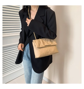 Elegante borsa a tracolla in pelle trapuntata beige con catena dorata su modella
