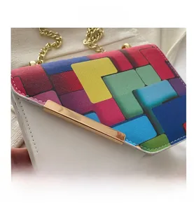 Close-up of leather crossbody bag with colorful geometric patterns and gold chain strap