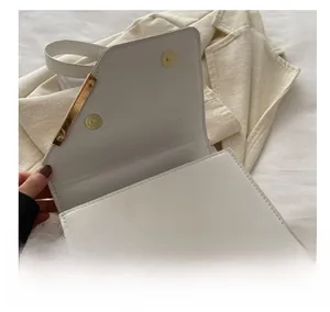 Detail of dual gold magnetic clasps on the white PU leather crossbody bag interior