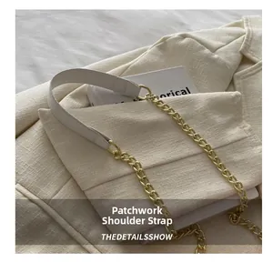 Detail of white litchi leather strap combined with gold metal chain on a crossbody bag