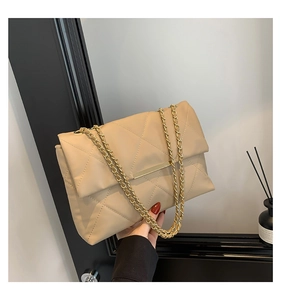 Dettaglio della borsa trapuntata beige con catena dorata e chiusura metallica elegante