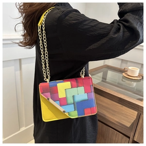 Detail of color-block crossbody bag with geometric patterns and golden chain strap