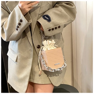 Detail of beige drawstring bucket bag featuring rich rabbit embossing and silver chain straps