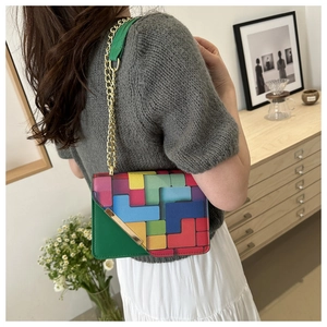 Detail of crossbody bag with colorful geometric patterns and gold triangular metal clasp