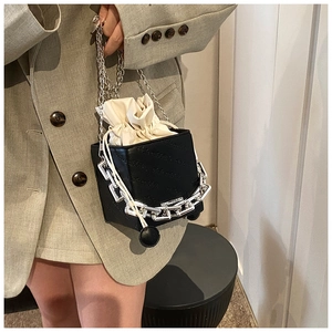 Detail of minimalist bucket bag featuring embossed letters and silver chain strap