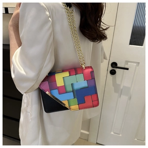 Detail view of colorful geometric patchwork pattern on a black crossbody chain bag