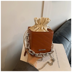 Detail of brown PU leather bucket bag with rich rabbit embossing and silver chain strap