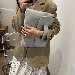 Minimalist light blue oversized clutch bag with pebbled leather texture and hand strap