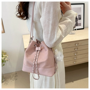 Detail of light pink drawstring bucket bag featuring metallic eyelets and chain strap
