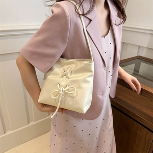 Cream satin tote bag with bow detail and ribbon laces shown on a female model