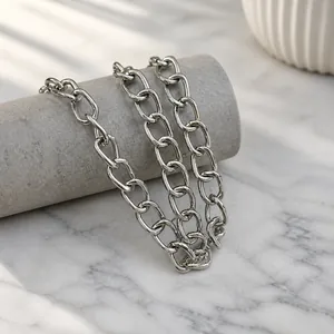 Dettaglio della tracolla a catena in metallo argento con maglie ovali lucide e intrecciate