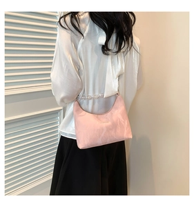 Dettaglio di pochette a pieghe in morbida pelle rosa con elegante catena di perle donna