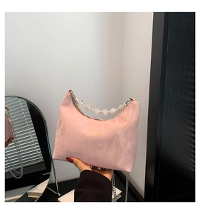 Dettaglio borsa hobo rosa con manico di perle, tracolla a catena e testo su pelle morbida