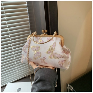 Detail of vintage shell bag featuring golden butterfly embroidery and metal ring handle