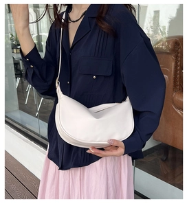 Lifestyle shot of white PU leather hobo bag worn crossbody with blue shirt and pink skirt