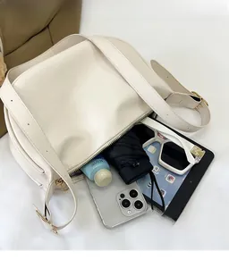 Detail view of cream white PU shoulder bag interior capacity with wide strap and gold zipper
