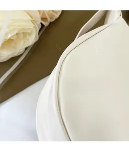 Detailed close-up of white leather handbag stitching and soft texture with rose decor