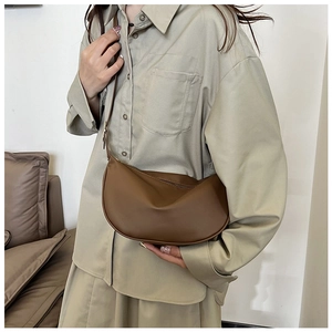 Macro view of dark brown semi-moon PU leather crossbody bag with golden metal buckle