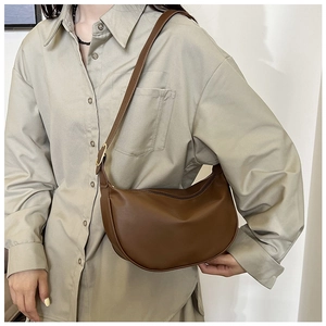 Detail of brown half-moon crossbody bag with smooth PU leather and gold hardware buckle