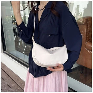 Detail of an off-white crescent crossbody bag featuring smooth leather and adjustable strap