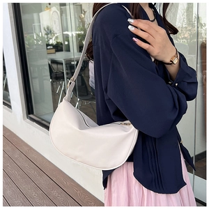 Detail of adjustable strap buckle on cream half-moon faux leather shoulder bag