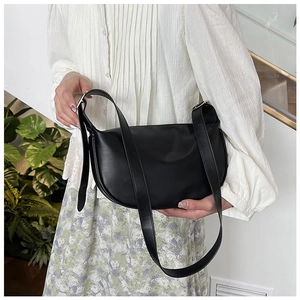 Detail of a black half-moon bag with matte leather finish and adjustable gold buckle